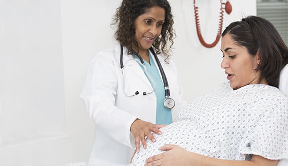 female doctor examining pregnant patient's belly